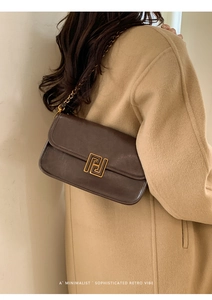 Sac bandoulière vintage marron avec boucle dorée porté par un mannequin en manteau