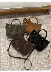 Detail of four matte leather bucket bags with woven knot handles and gold hardware