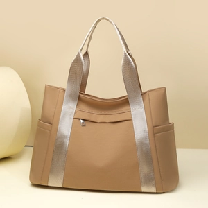 Close-up of khaki nylon tote bag showing front zipper pocket and side compartments