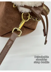 Détail de la boucle en métal doré sur le sac seau en daim marron avec bordure en peluche