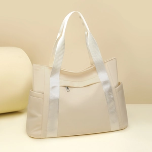 Detail view of large nylon tote bag in beige with wide straps and functional side pockets