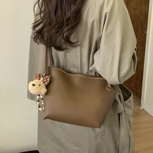 Close-up of brown litchi textured tote bag with a cute plush puppy pendant detail