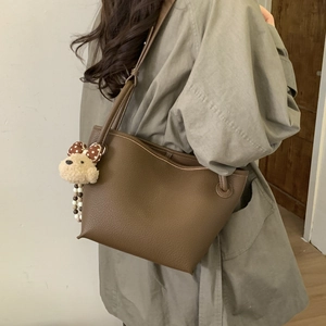 Detail of dark brown pebble leather tote bag with a cute plush bear charm accessory