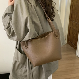 Close-up of minimalist dark brown lychee leather tote bag with unique ring strap design