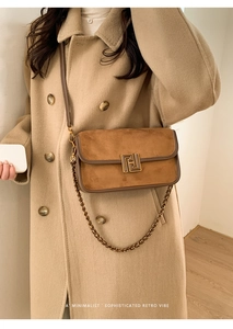 Détail d'un sac bandoulière en daim marron avec boucle dorée et bandoulière chaîne