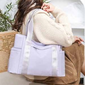 Lifestyle shot of a woman carrying a light purple nylon tote bag in a cozy indoor setting