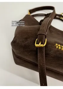 Detail of adjustable strap with gold buckle on coffee suede bucket bag for women