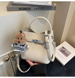 Close-up of beige lychee leather bucket bag with silver turn-lock and dog charm