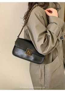 Détail du sac à rabat noir avec fermoir géométrique doré et bandoulière chaîne