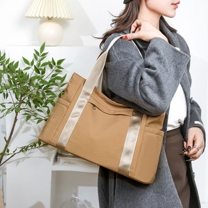 Detail view of khaki nylon tote bag with wide strap on model in minimalist interior