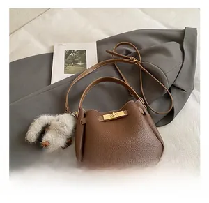 Detail of brown litchi pattern bucket bag with gold twist lock and plush rabbit charm