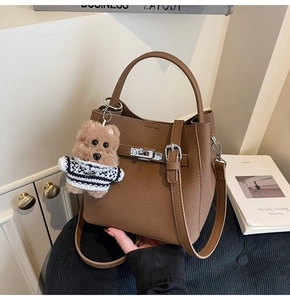 Detailed view of brown litchi grain bucket bag with silver clasp and bear charm