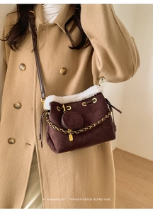 Détail du sac seau marron foncé en suédine avec bordure en peluche blanche et chaîne dorée