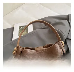 Detail of dark brown lychee leather bucket bag with golden twist-lock closure