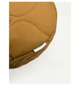 Détail macro du tissu matelassé caramel et de l'étiquette latérale du sac à bandoulière