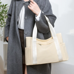 Detailed view of beige nylon tote bag showing spacious compartments and wide strap