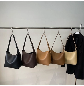 Five minimalist pebble leather hobo bags in various colors hanging on a metal display rack