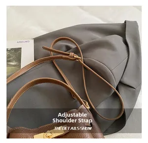 Detail of adjustable strap and gold buckle on a brown pebble leather bucket bag