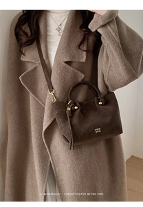 Detail of dark brown suede bucket bag featuring knotted handle and gold metal COIH 2DN logo