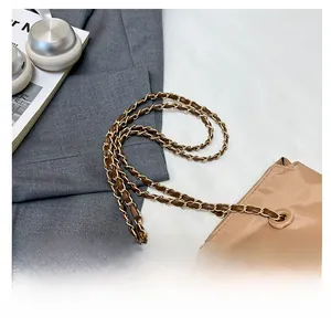 Détail du sac seau en nylon avec bandoulière chaîne et écusson en cuir embossé