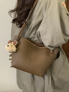 Brown lychee leather bucket tote bag with cute plush puppy charm shown on model