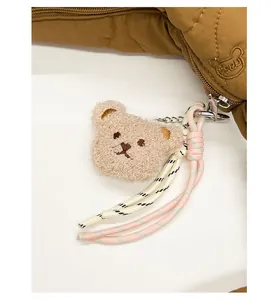 Détail d'une breloque ours en peluche avec corde tissée sur un sac matelassé marron