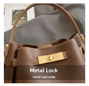 Detail of dark brown pebble leather bucket bag with gold hardware twist lock and handle