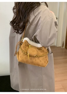 Détail du sac seau en daim marron avec bordure en fourrure, chaîne et mini pochette