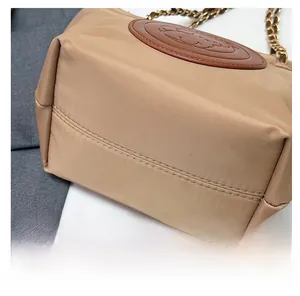 Détail de la double couture précise sur un sac seau en nylon kaki avec bandoulière chaîne