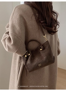 Close-up of a dark brown leather bucket bag on a wool coat highlighting retro textures