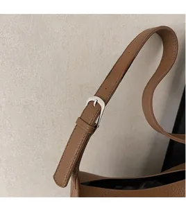 Detail of adjustable brown pebble leather shoulder strap with silver buckle and fine stitching