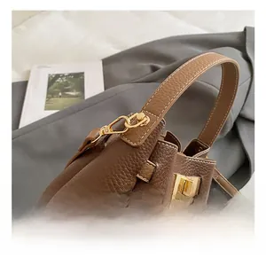 Detail of gold-tone hardware and latch on a brown lychee pattern leather bucket bag