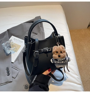 Black litchi grain bucket bag with a cute teddy bear charm and silver twist lock detail