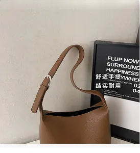 Close-up of brown litchi grain leather bucket bag with adjustable silver buckle strap