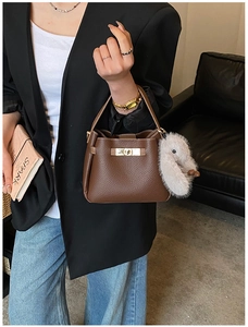 Brown lychee-grain leather bucket bag with gold twist lock and plush duck charm