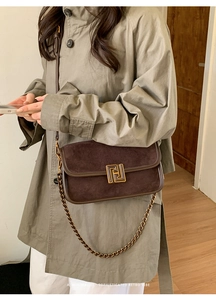 Détail du sac bandoulière en daim marron foncé avec fermoir géométrique doré et chaîne