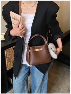 Detail of dark brown pebble leather bucket bag with gold buckle and plush bunny charm