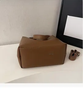 Detail of soft brown pebble leather handbag with short handle and matching shoulder strap