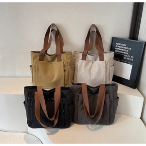 Detail of canvas tote bags in four colors with wide straps and large front pockets