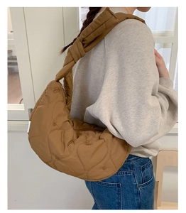 Détail de la couture en cœur sur un sac besace marron porté à l'épaule par un mannequin