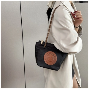 Detail of black nylon shoulder bag featuring golden chain strap and cute dog leather patch