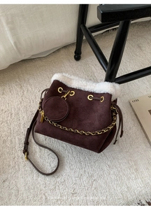 Détail du sac seau en daim marron foncé avec bordure en fausse fourrure et chaîne métal