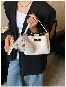 Detail of off-white lychee texture leather handbag with gold twist lock and rabbit charm