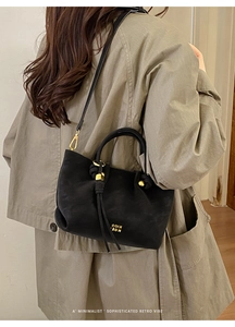 Detail of vintage black leather bucket bag with gold hardware and drawstring closure