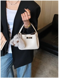 Detail of white litchi grain leather bucket bag with gold lock and plush rabbit charm