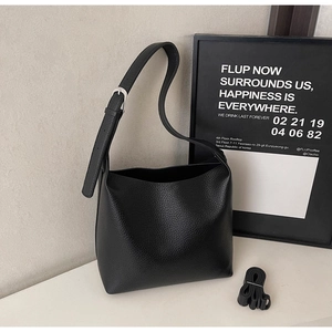 Close-up of black lychee-textured leather tote bag with silver metal buckle detail