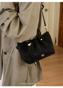 Close-up of black matte shoulder bag with gold sphere studs and retro branding details