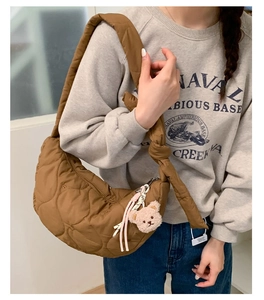 Sac bandoulière matelassé marron avec charme ours en peluche porté par un mannequin en style