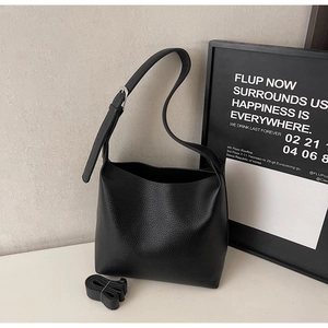 Close-up of black pebble texture tote bag with wide strap and metallic adjustment buckle
