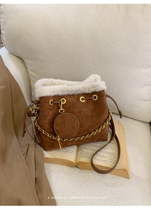 Détail du sac seau en daim marron avec bordure en peau lainée et chaîne dorée